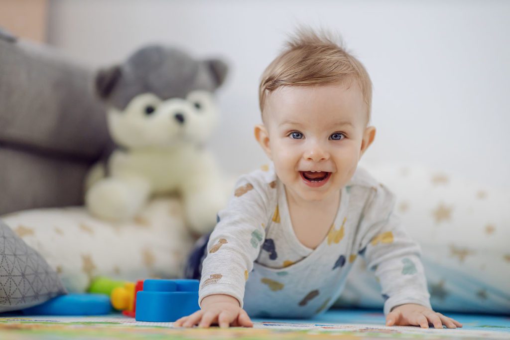 Adorable cheerful laughing blond little boy crawling at a Preschool & Daycare Serving San Antonio, TX