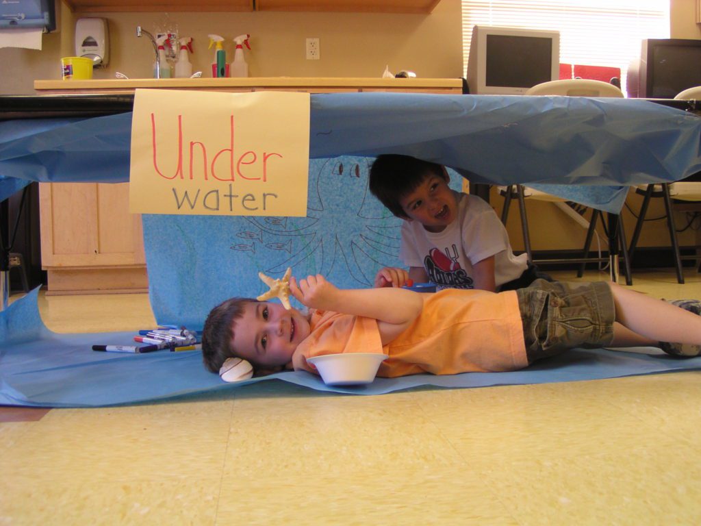 boys holding sea creatures under a table at a Preschool & Daycare Serving San Antonio, TX