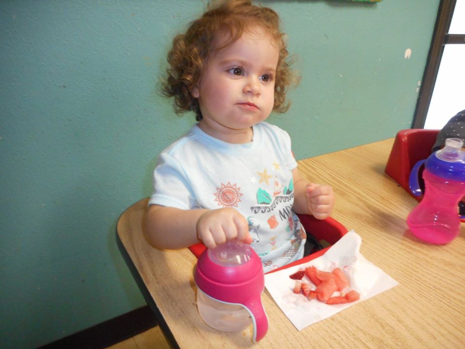 cute baby girl eating strawberries at a Preschool & Daycare Serving San Antonio, TX