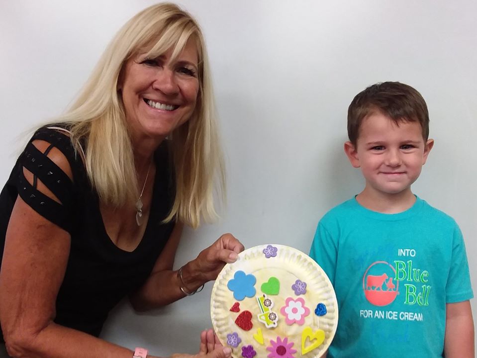 teacher and boy showing off art in class at a Preschool & Daycare Serving San Antonio, TX